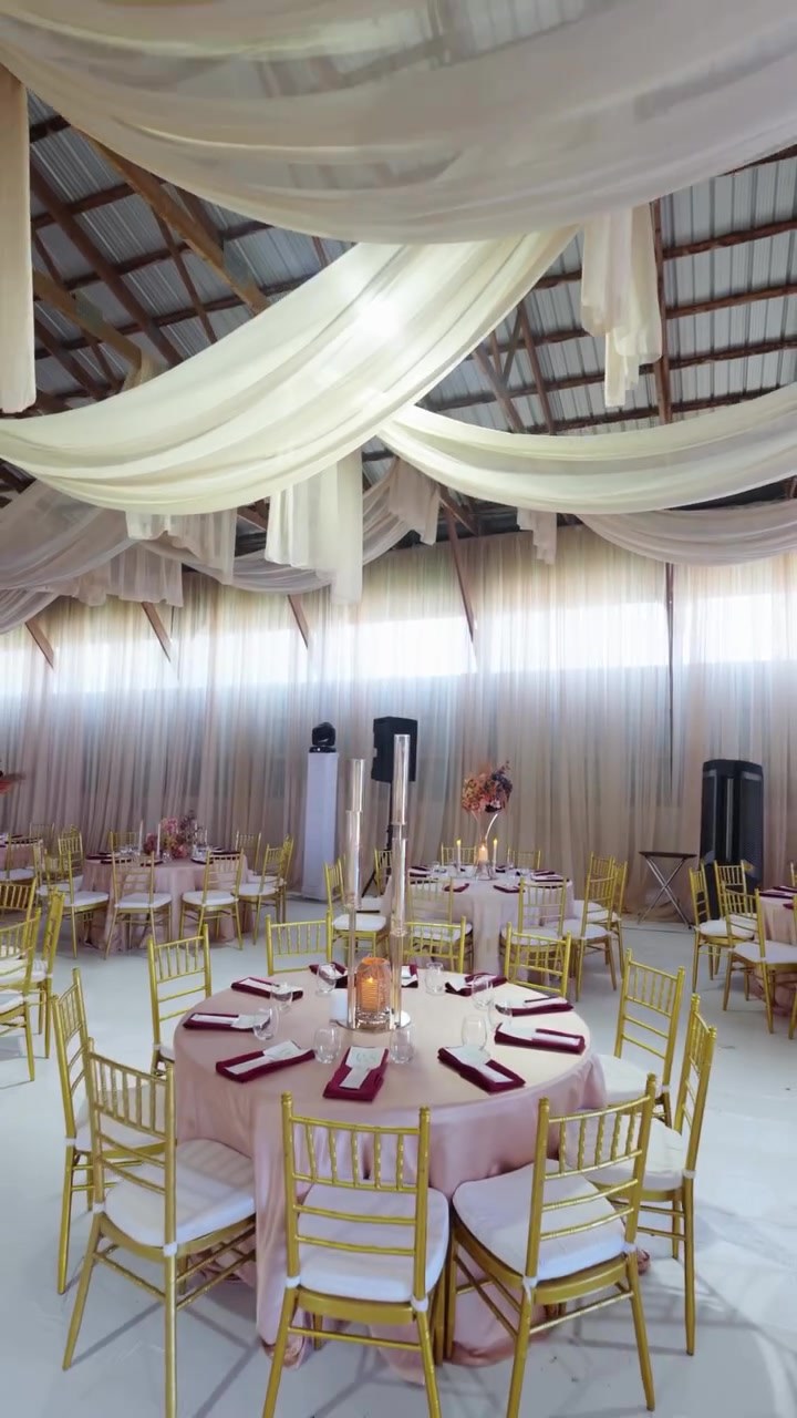 Wedding reception hall draped wall to wall, set for hundreds of guests